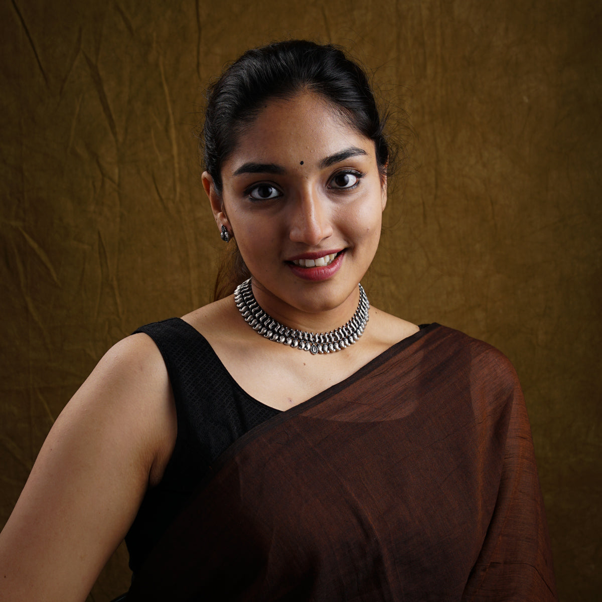 a woman in a brown dress with a necklace on