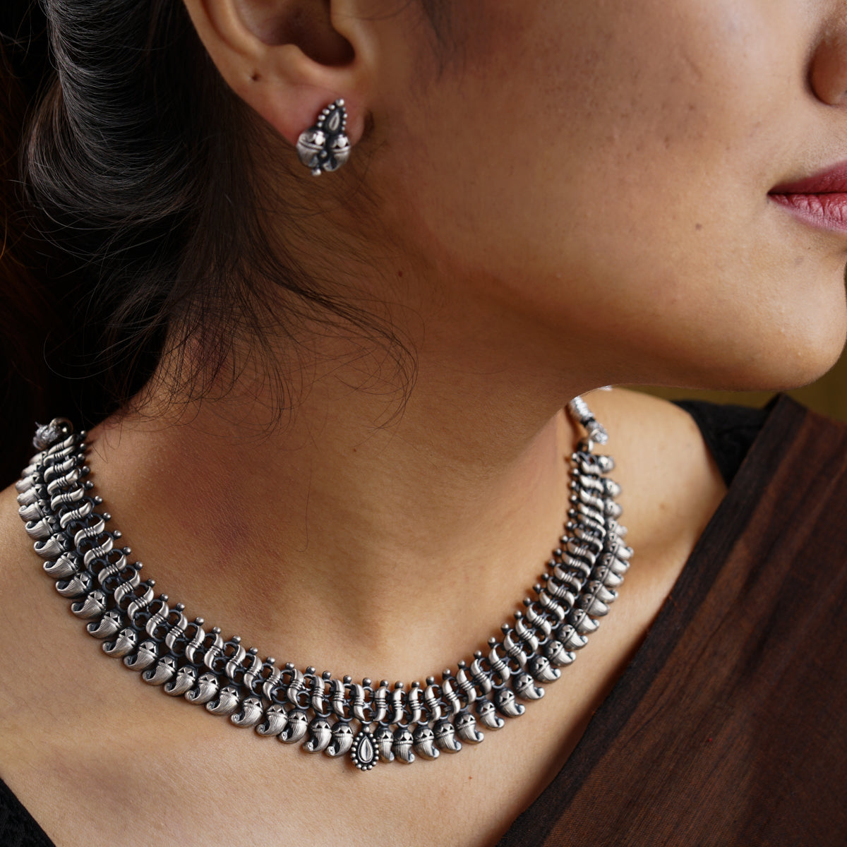 a close up of a woman wearing a necklace and earrings