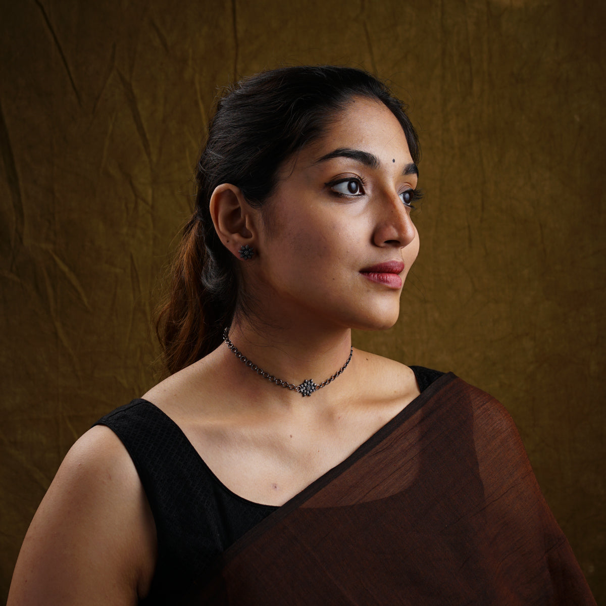 a woman wearing a brown sari and a necklace