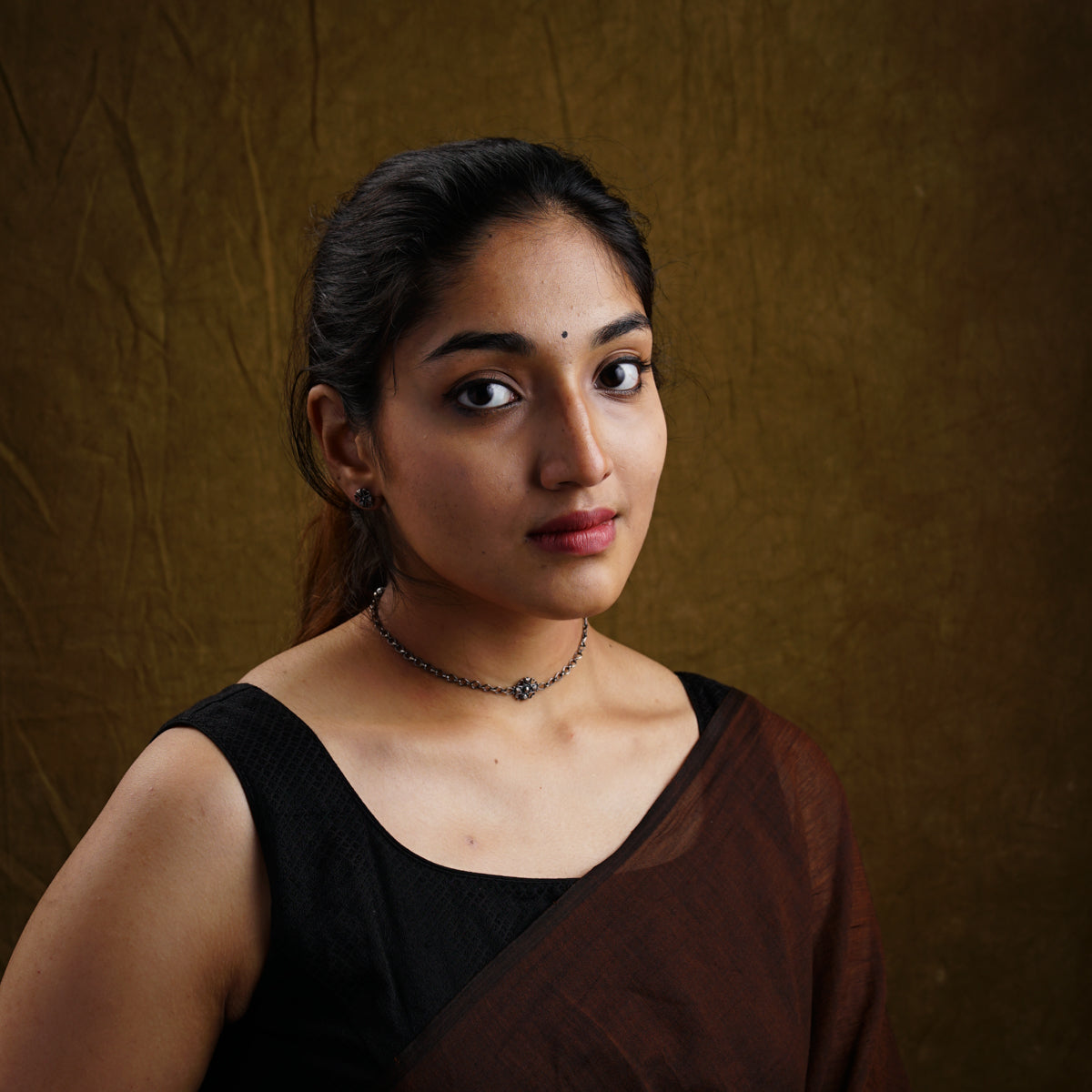 a woman in a brown sari poses for a picture