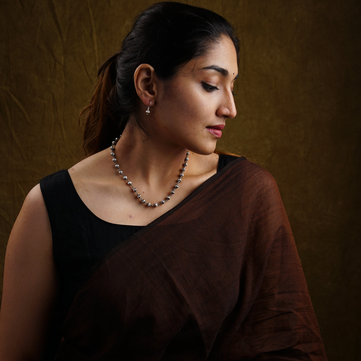 a woman wearing a necklace with pearls on it