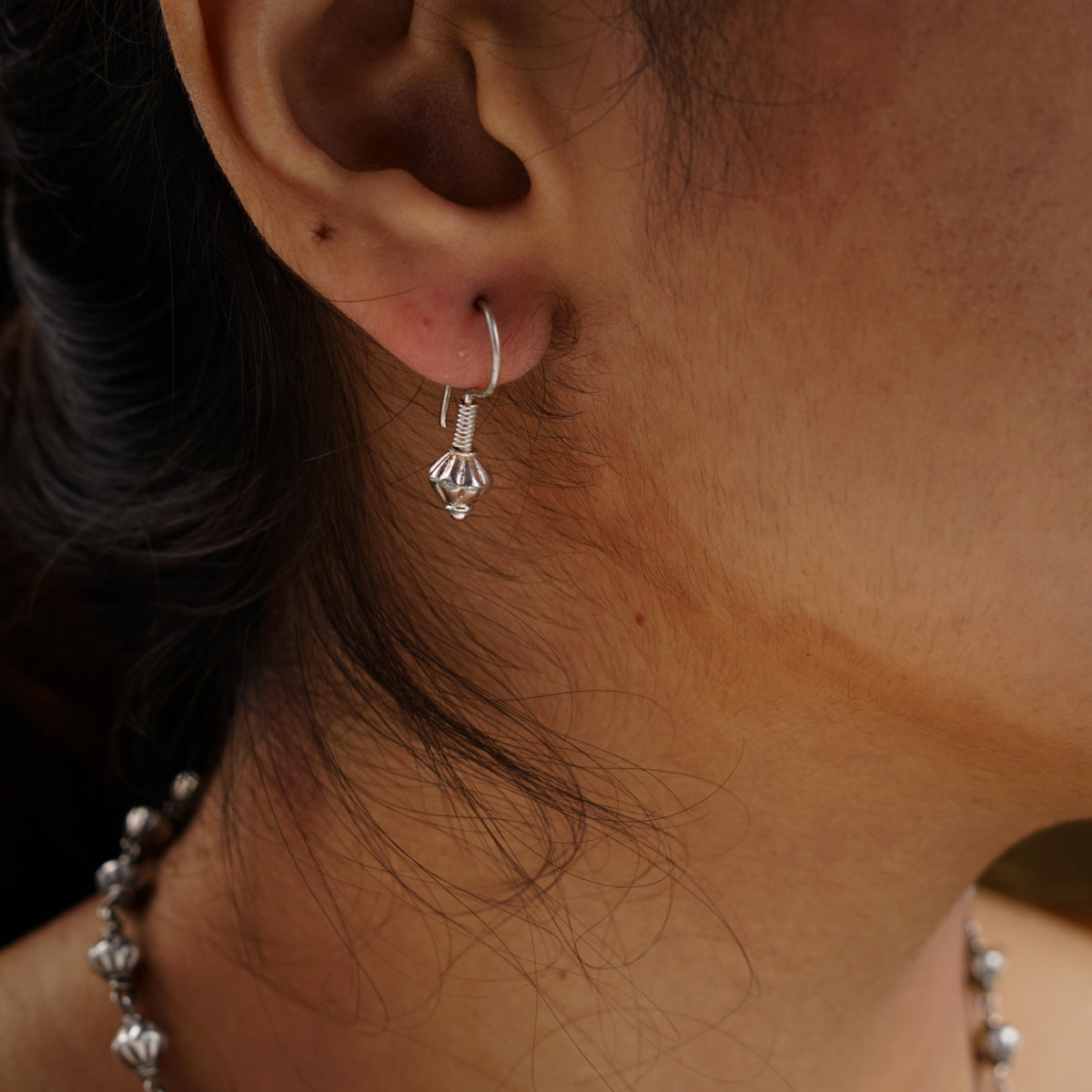 a close up of a person wearing a necklace and earrings