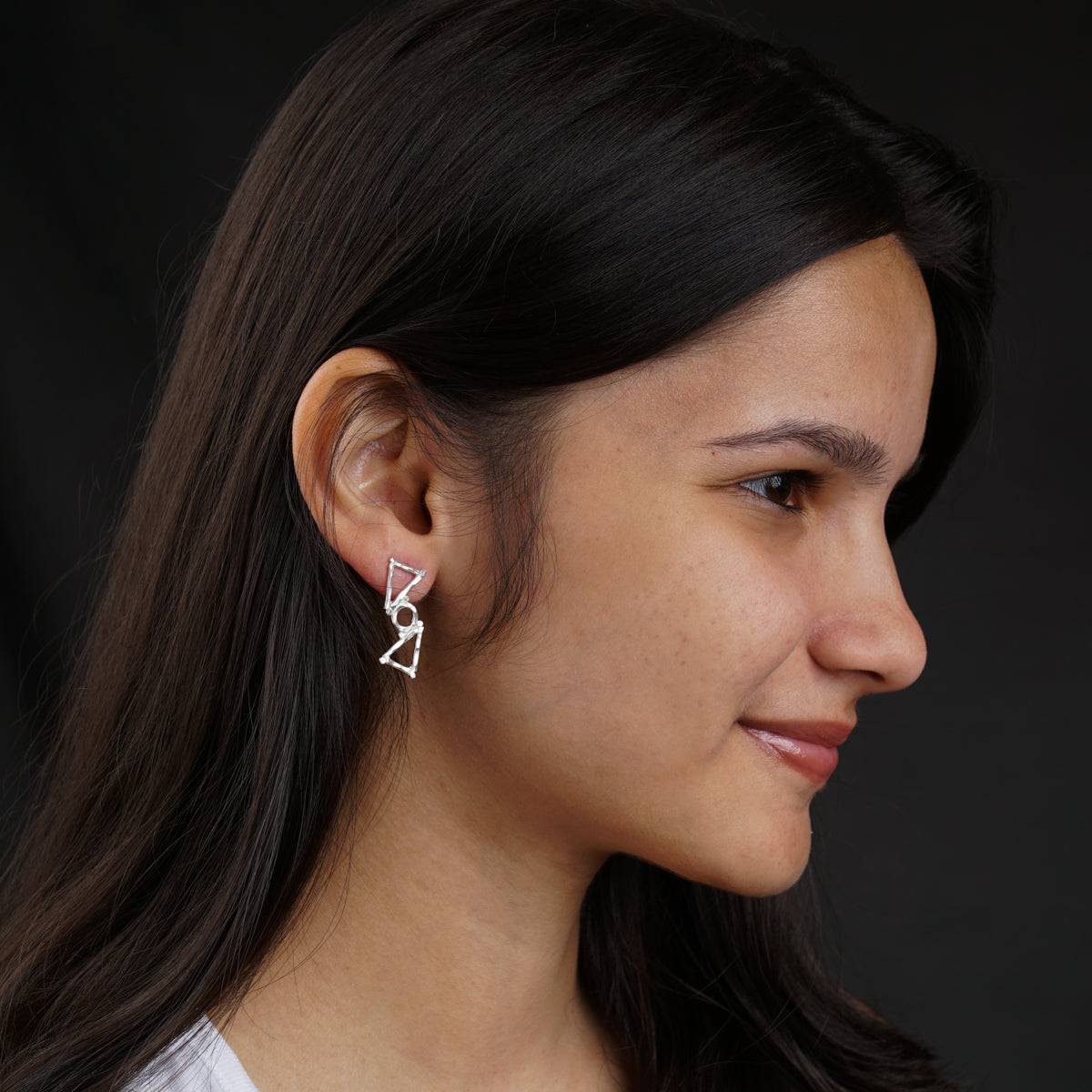 a woman wearing a pair of silver earrings