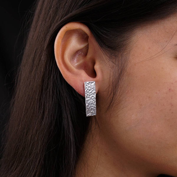 a close up of a person wearing a pair of earrings