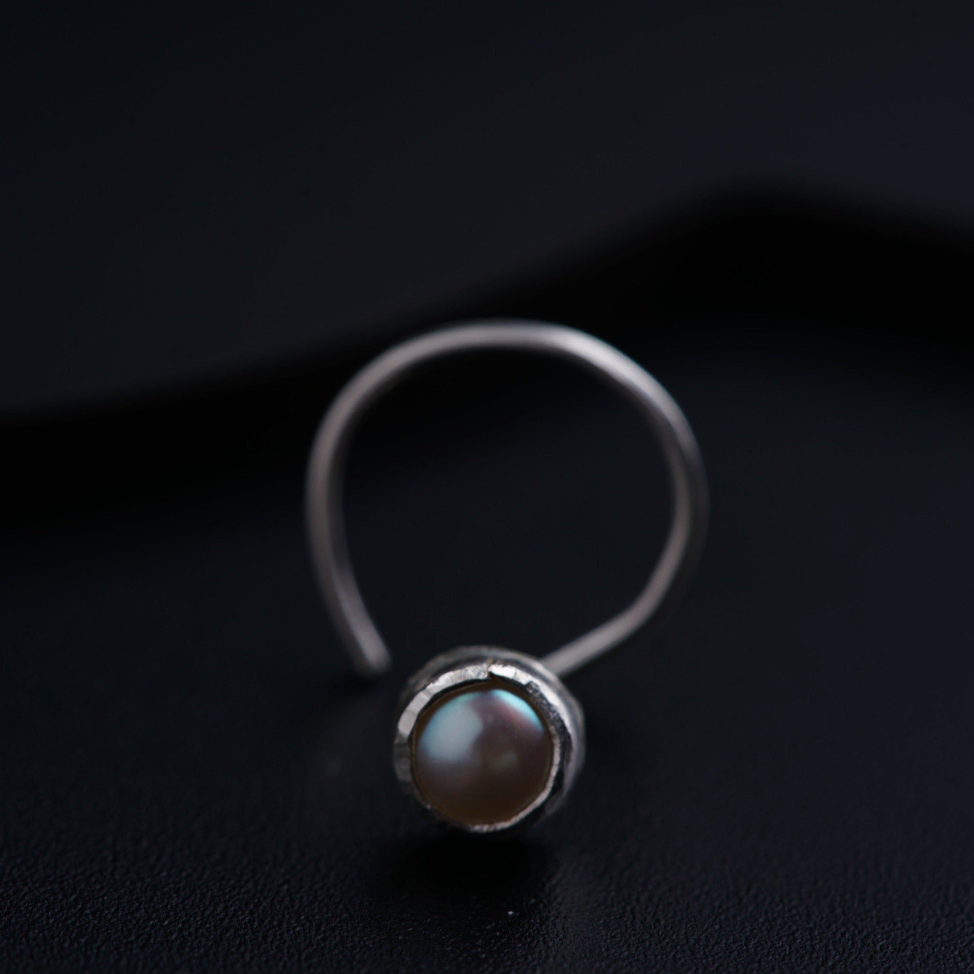 a close up of a ring with a pearl on it