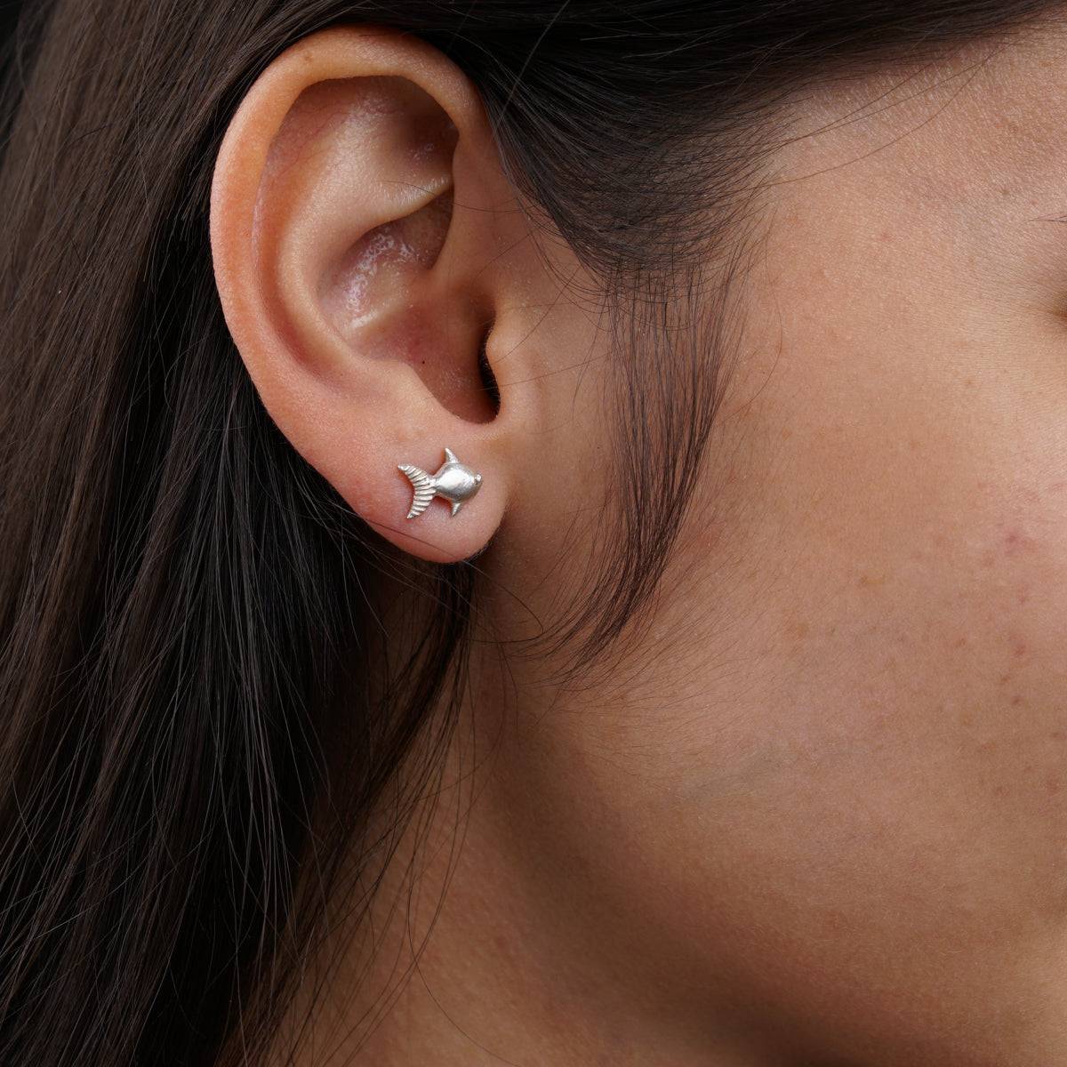 Handcrafted silver fish stud earrings close-up detailing