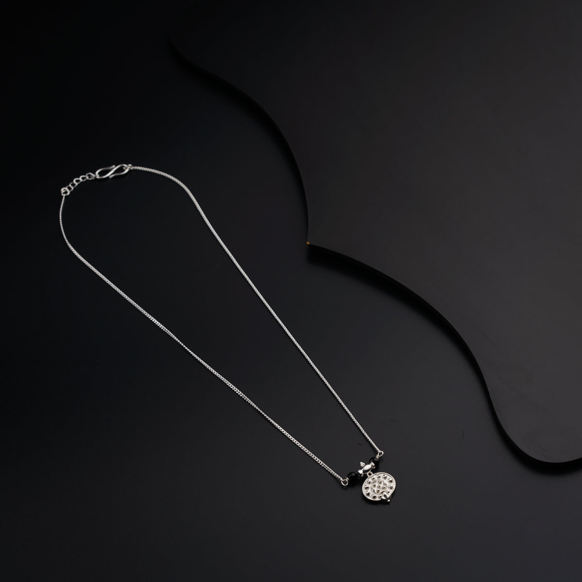 a black and white photo of a necklace on a black background
