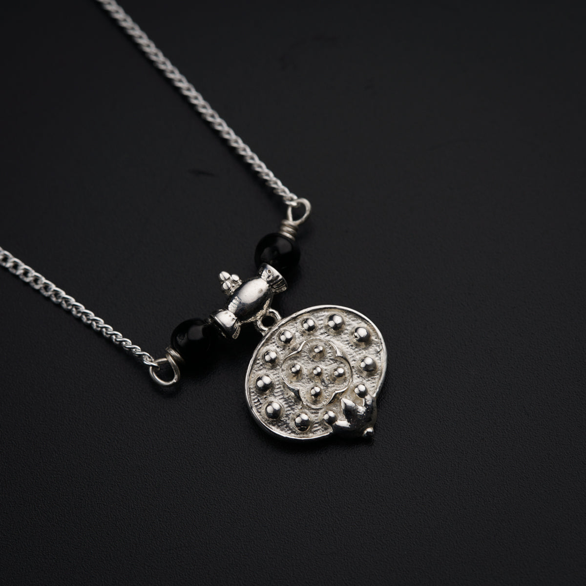 a black and white photo of a necklace on a black surface