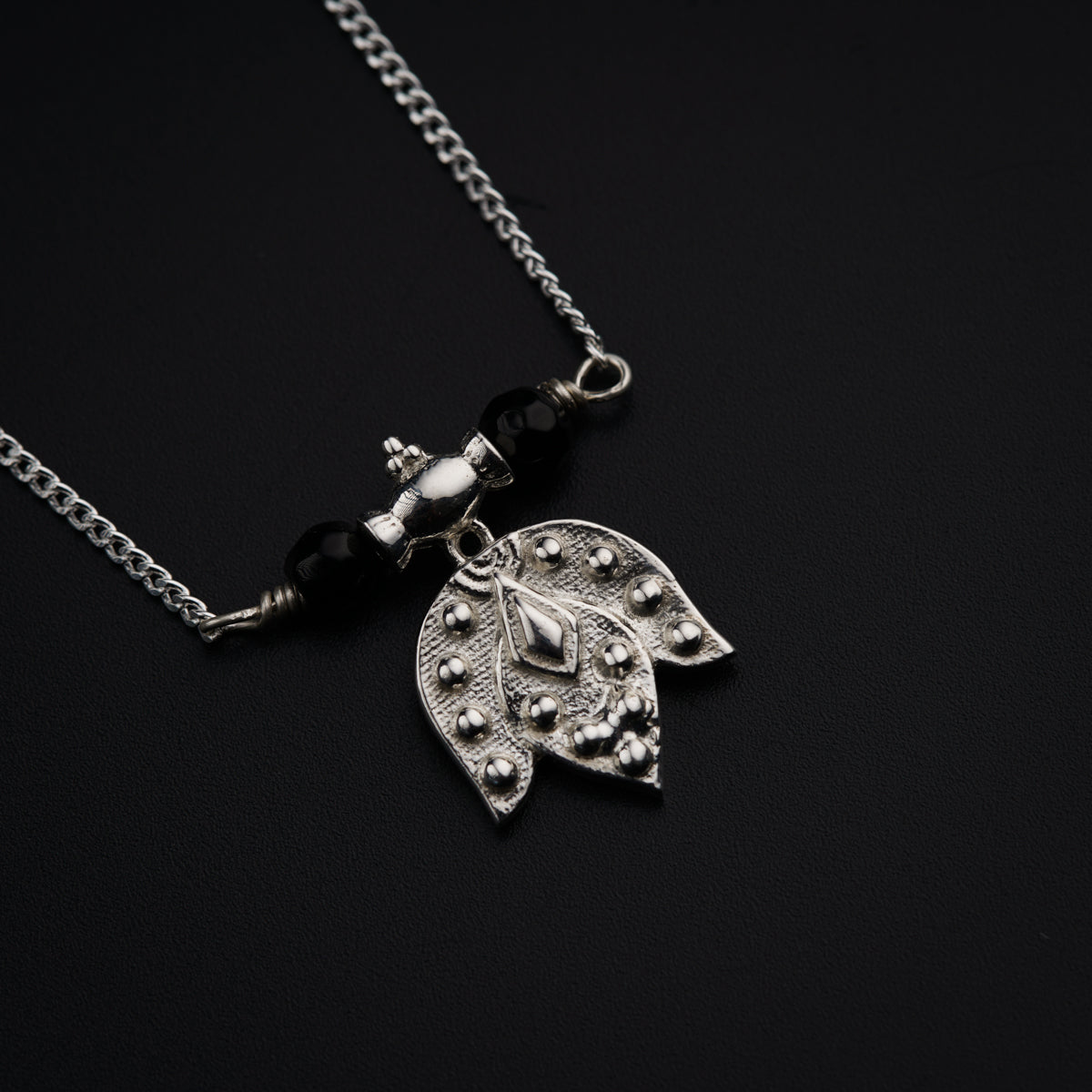 a silver necklace with a leaf on it