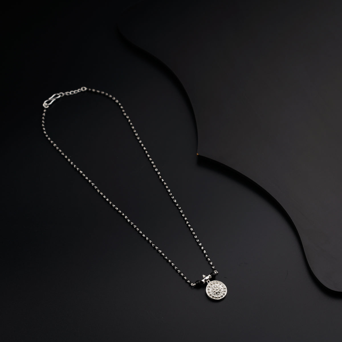 a black and white photo of a necklace on a black background