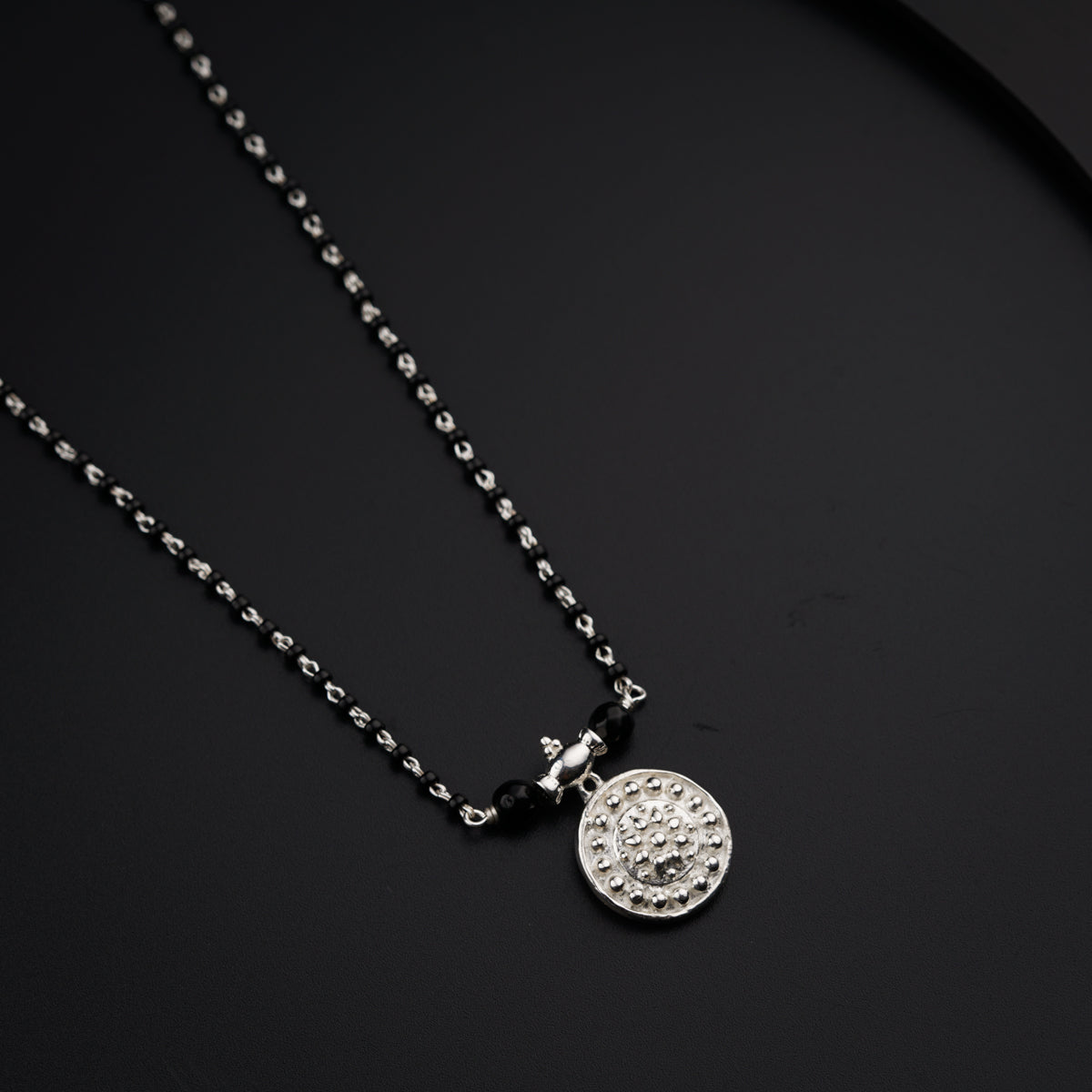 a necklace with a medallion on a black surface