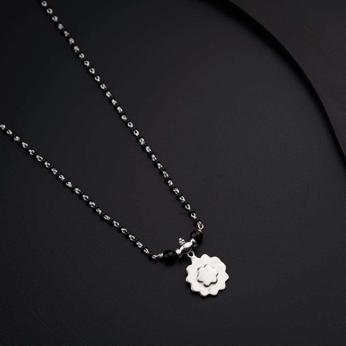 a black and white photo of a necklace with a flower on it