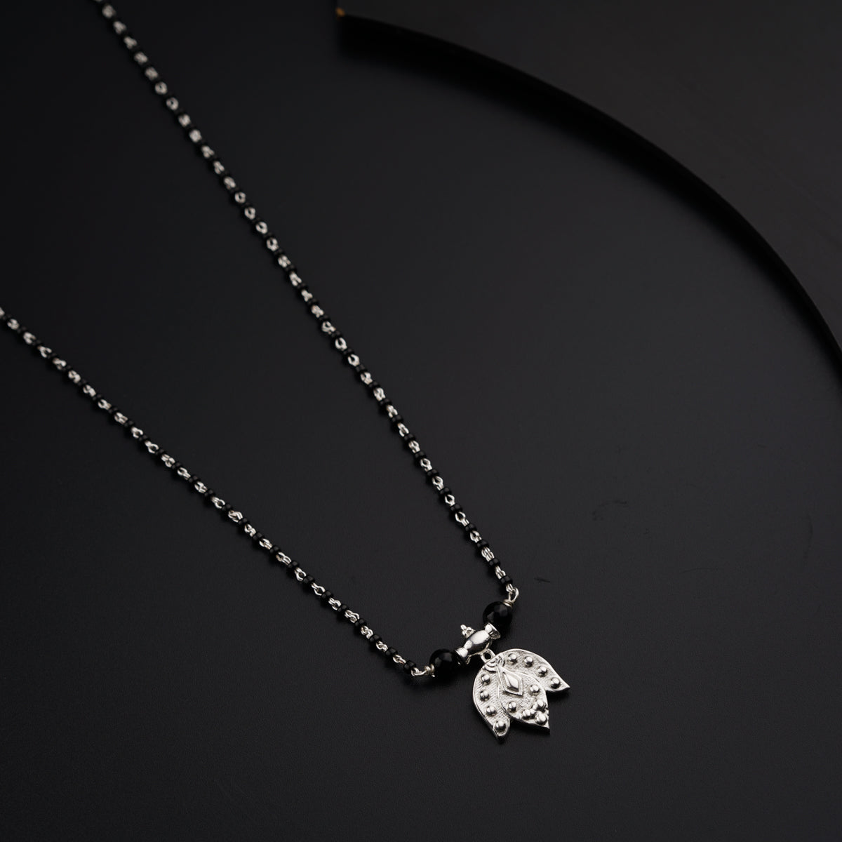 a black and white photo of a necklace on a black surface