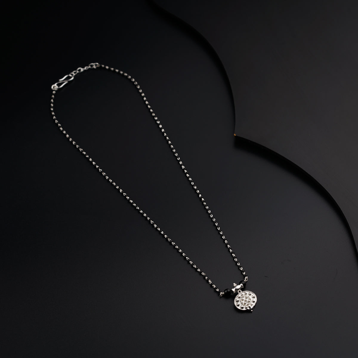a black and white photo of a necklace on a black background