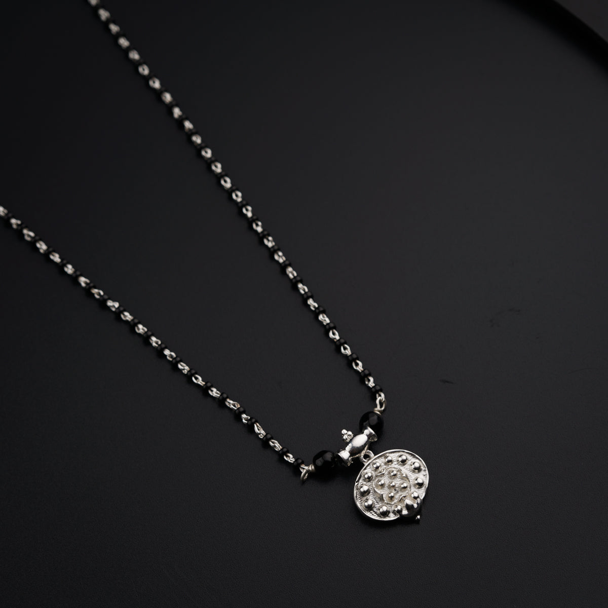 a black and white photo of a necklace on a black surface