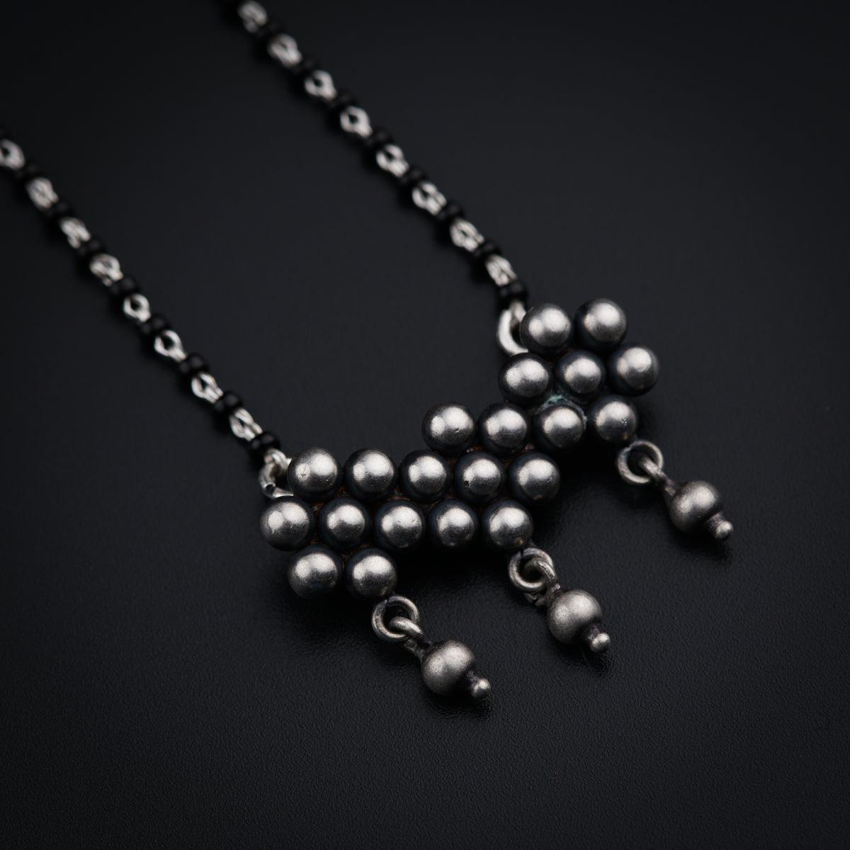 a silver ball chain is shown on a black surface