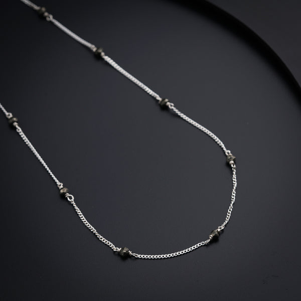 a silver necklace with beads on a black surface