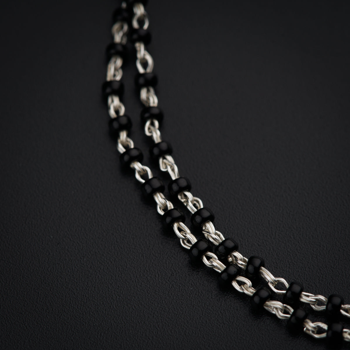 a black and silver necklace on a black surface