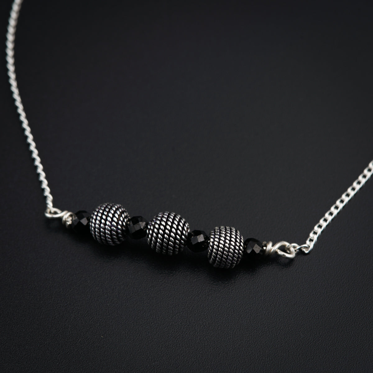 a black and white necklace on a black surface