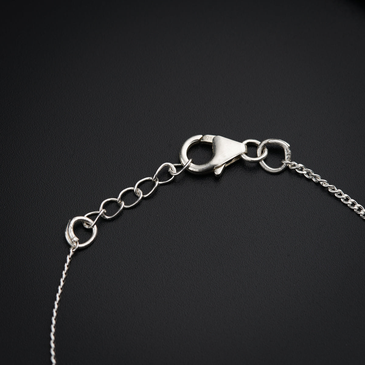 a close up of a silver bracelet on a black surface