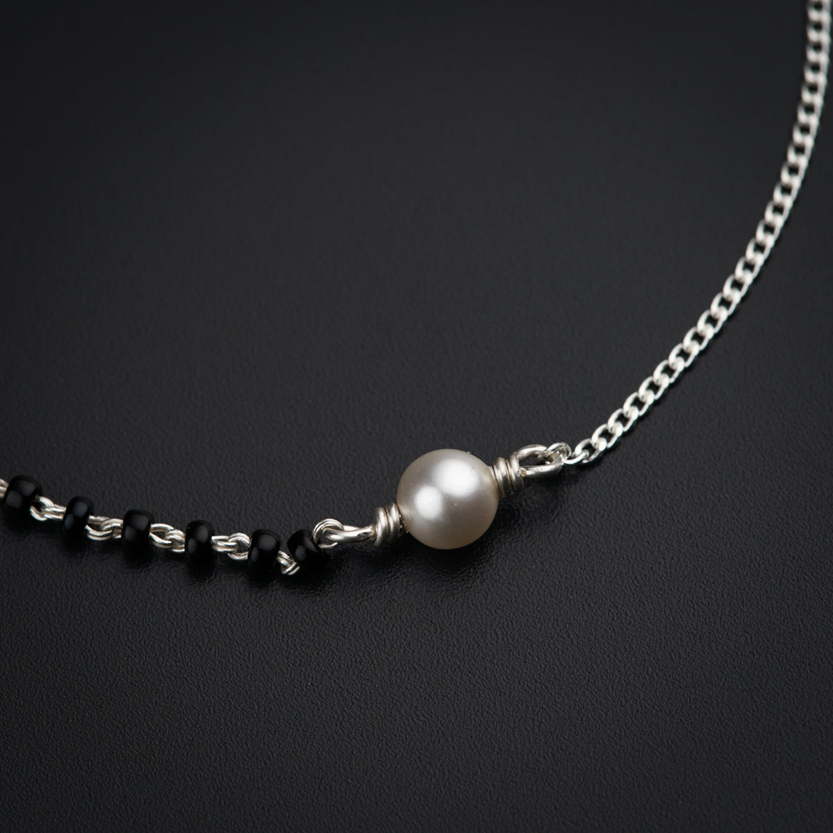 a necklace with a white pearl on a black background