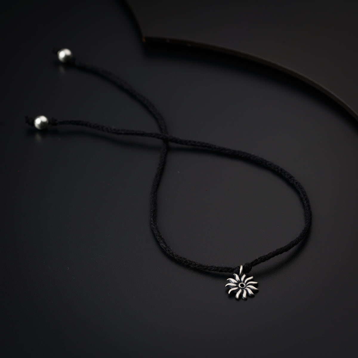 a black cord necklace with a flower pendant