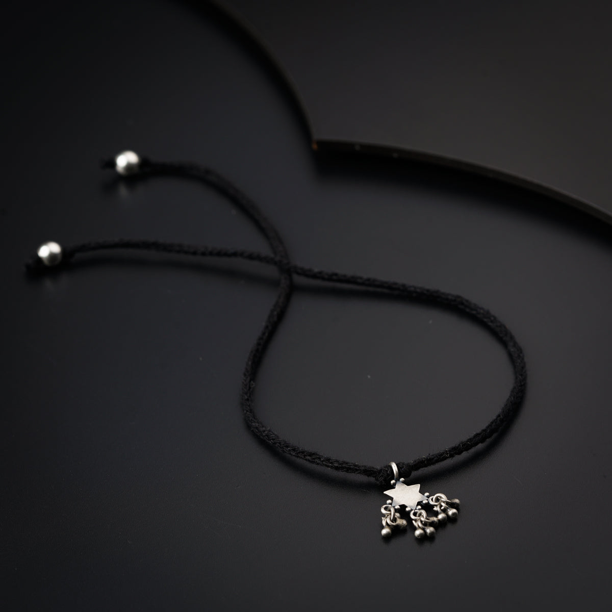 a black cord necklace with a silver skull charm