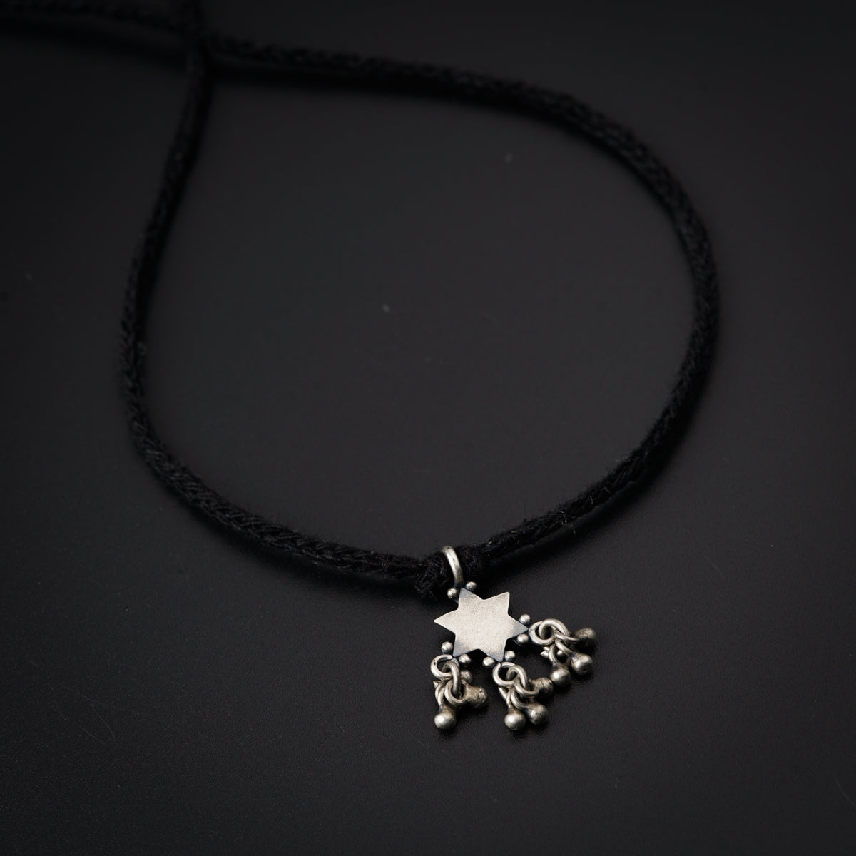 a black cord necklace with a silver star on it