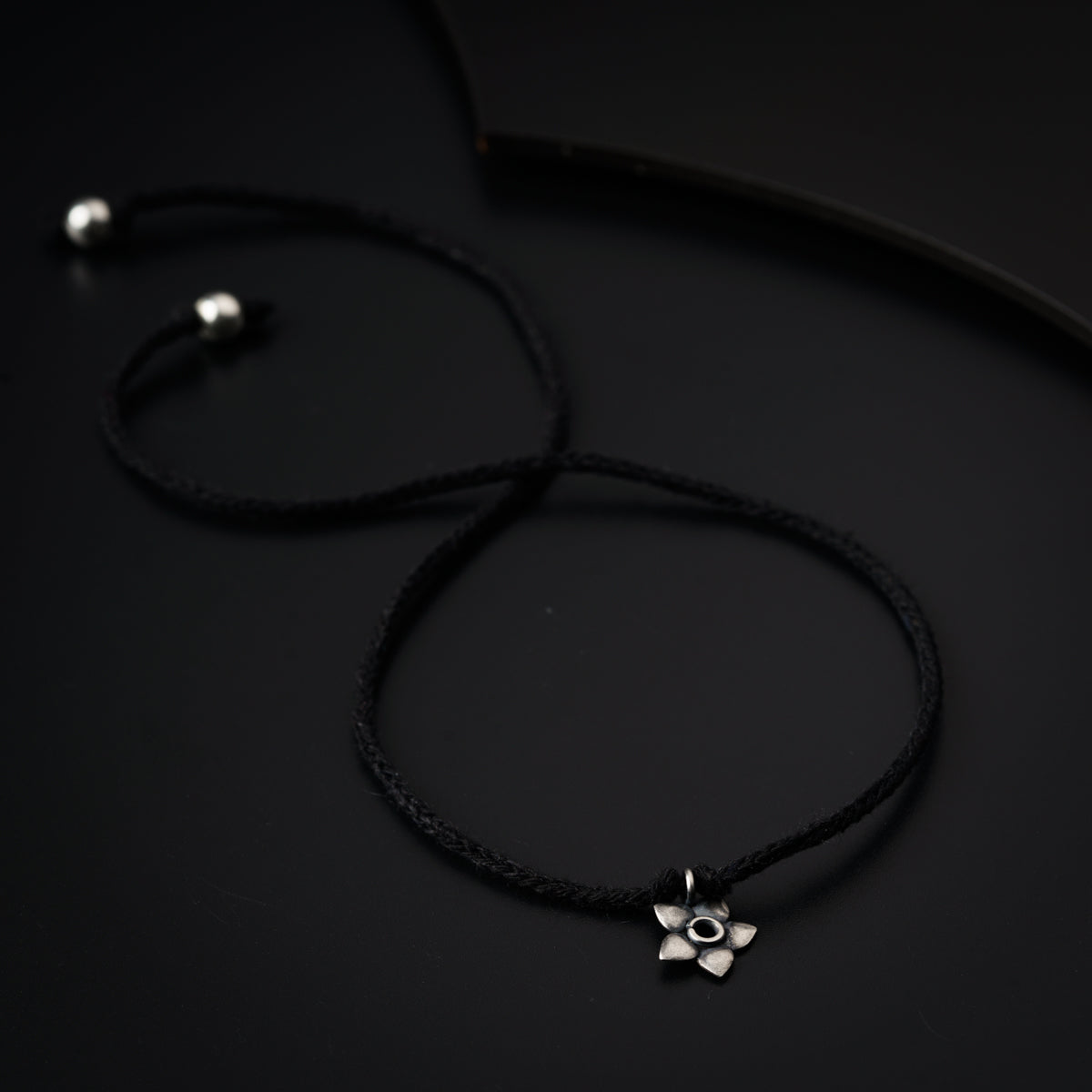 a black cord with a silver flower on it