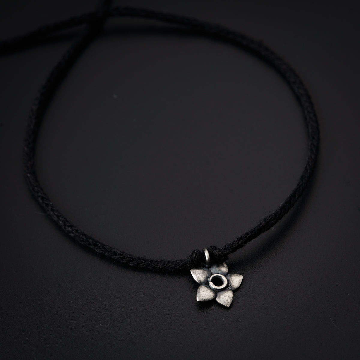 a black cord with a silver flower on it