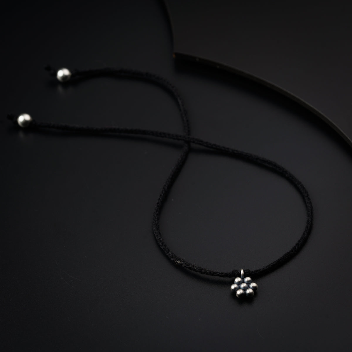 a black cord with a silver cross on it