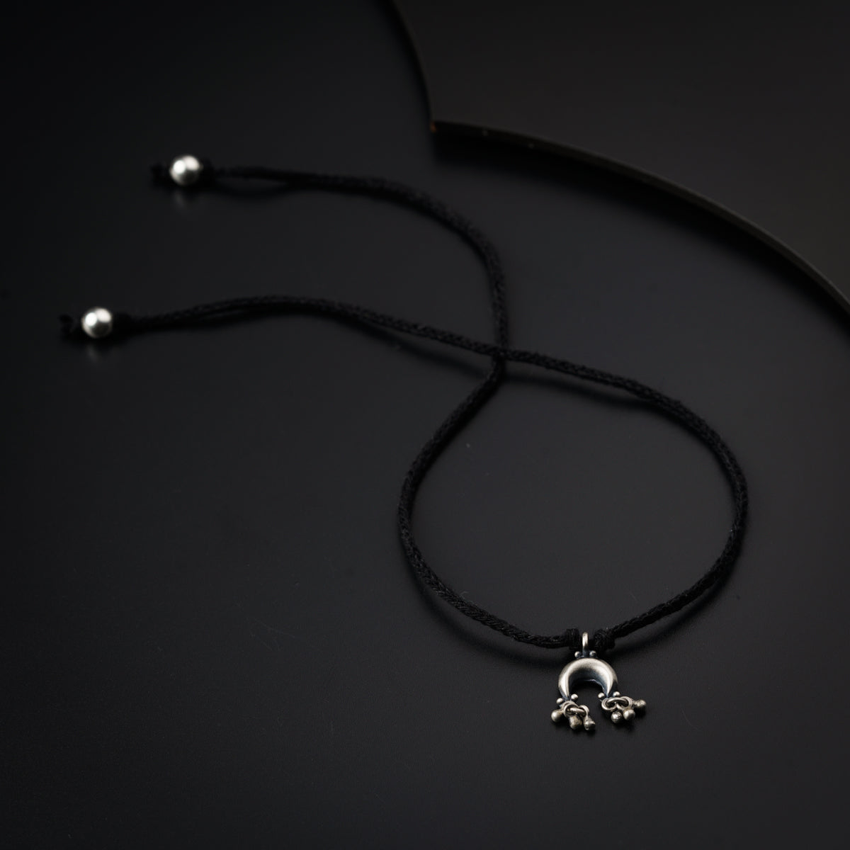 a black cord with a silver pendant on it