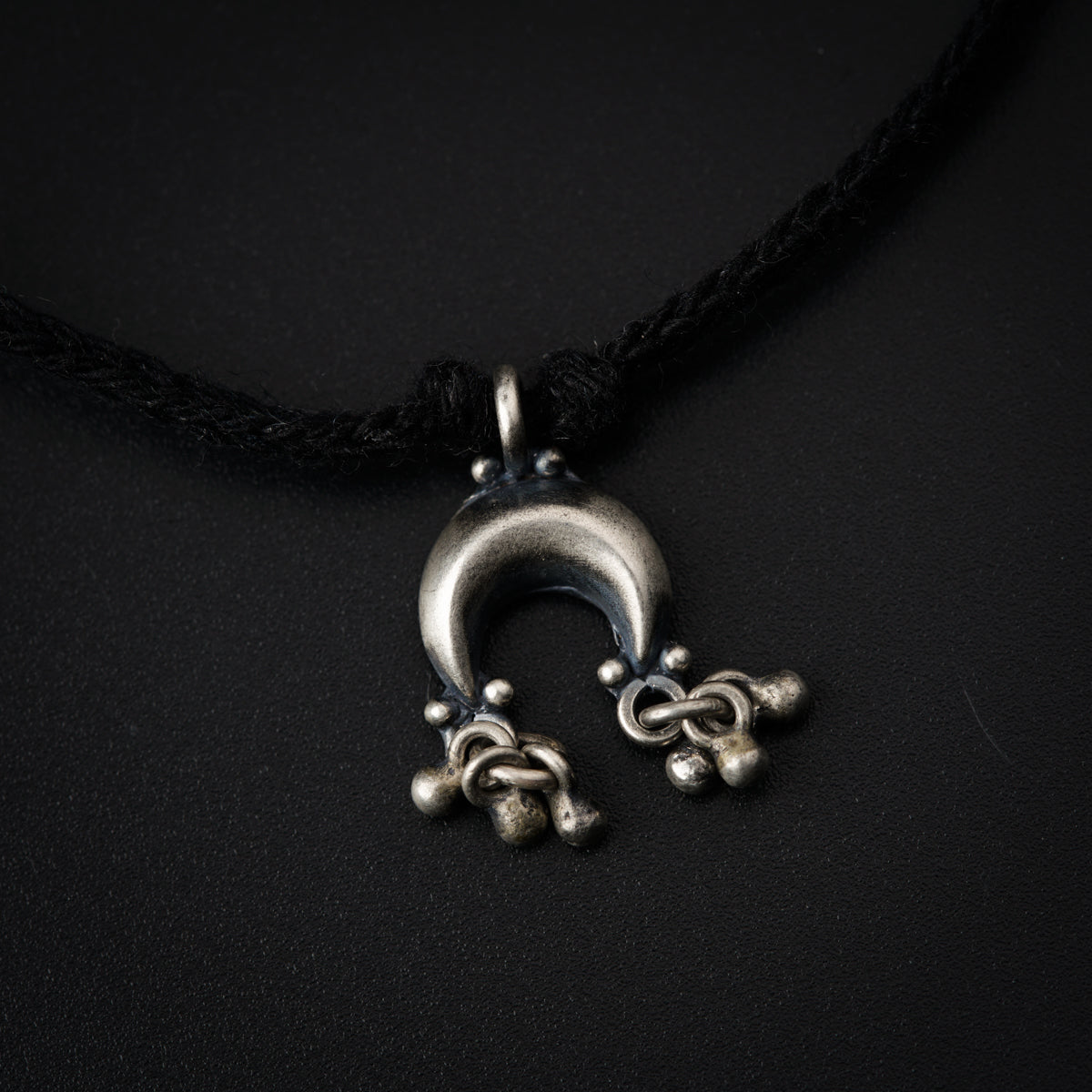 a necklace with a metal object hanging from it's side