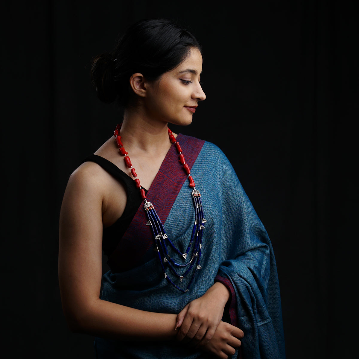 a woman in a blue sari with a red beaded necklace