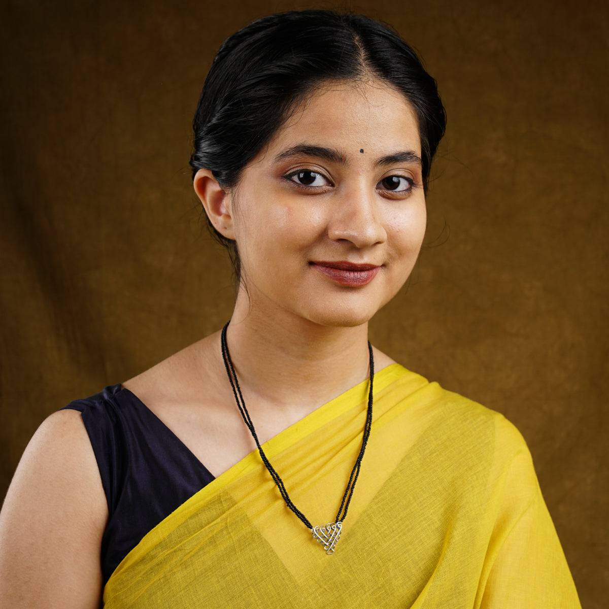 a woman wearing a yellow sari and a necklace