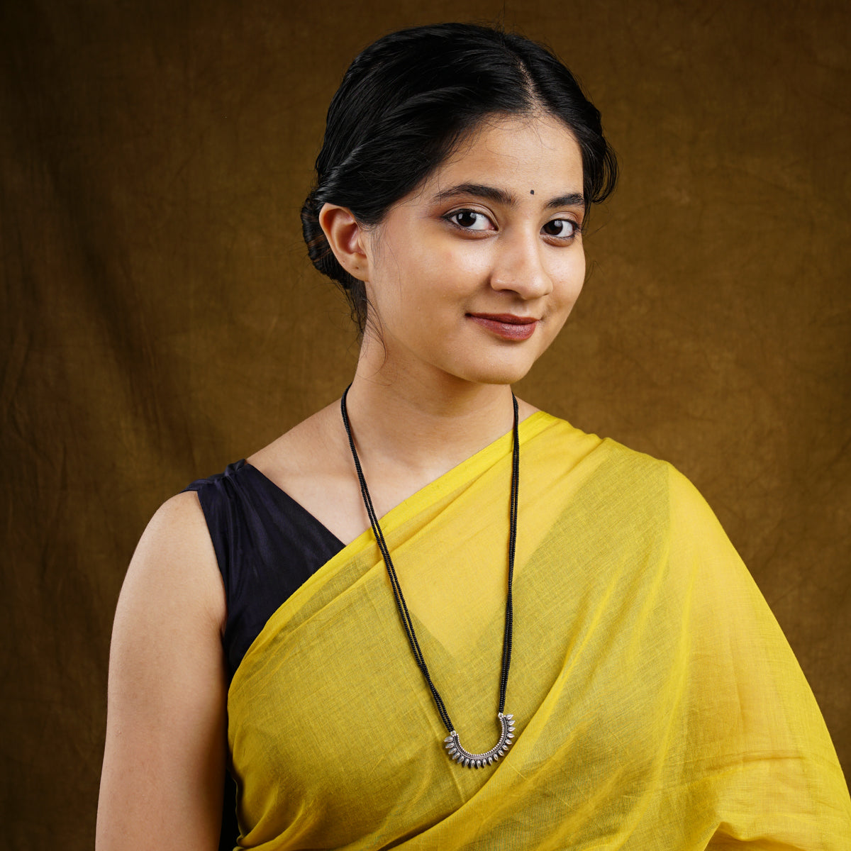 a woman wearing a yellow sari and a necklace