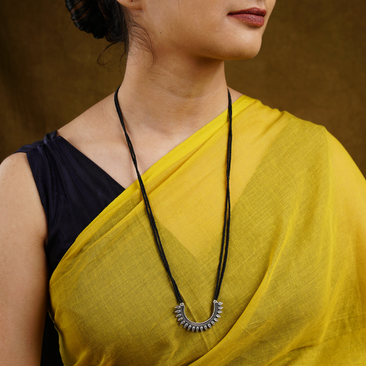 a woman wearing a yellow sari and a necklace