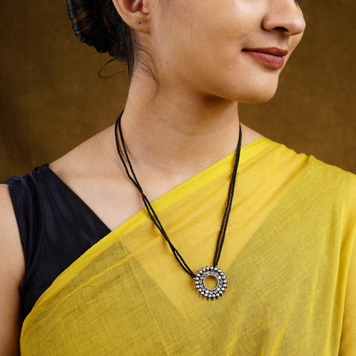 a woman wearing a yellow shirt and a necklace