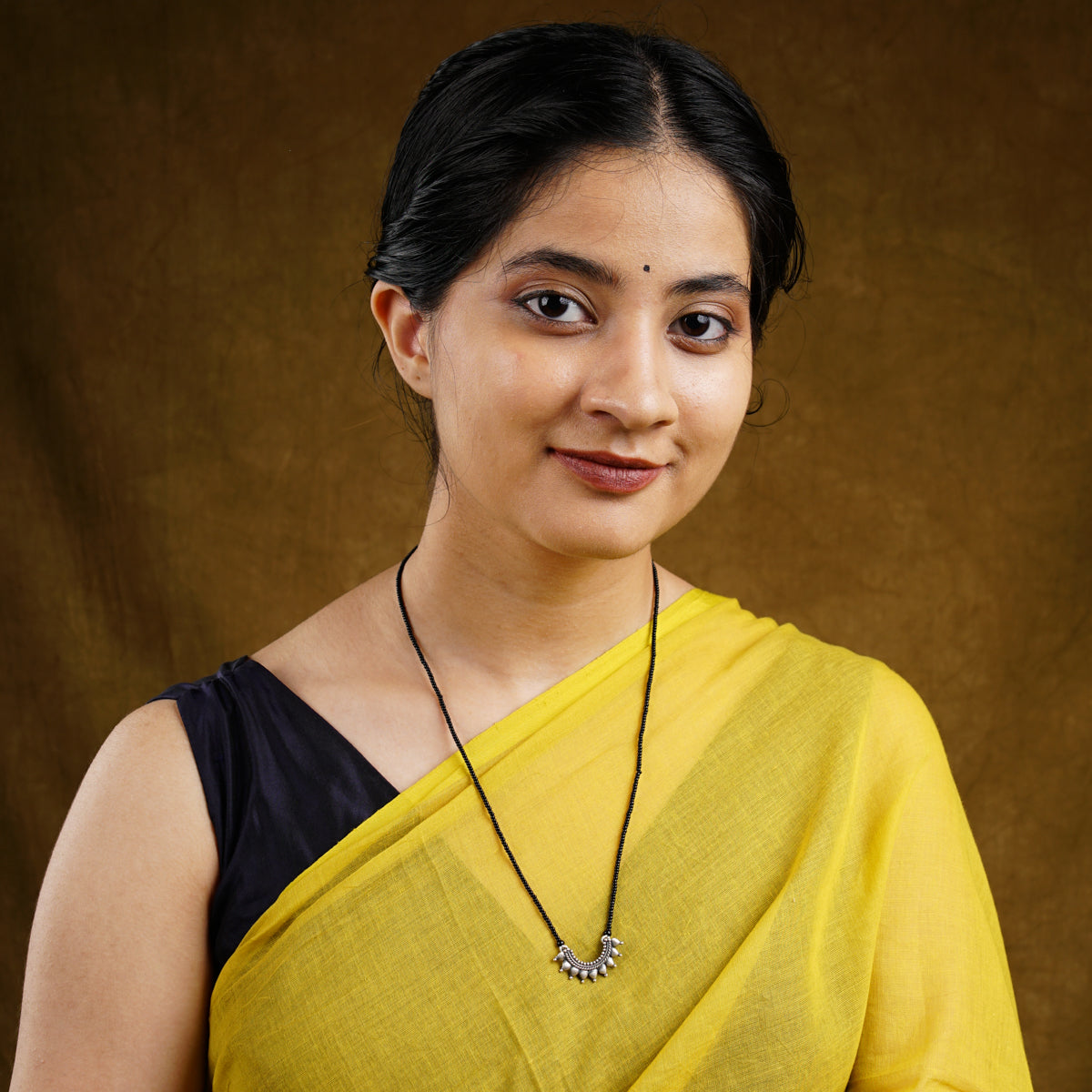 a woman wearing a yellow sari and a necklace