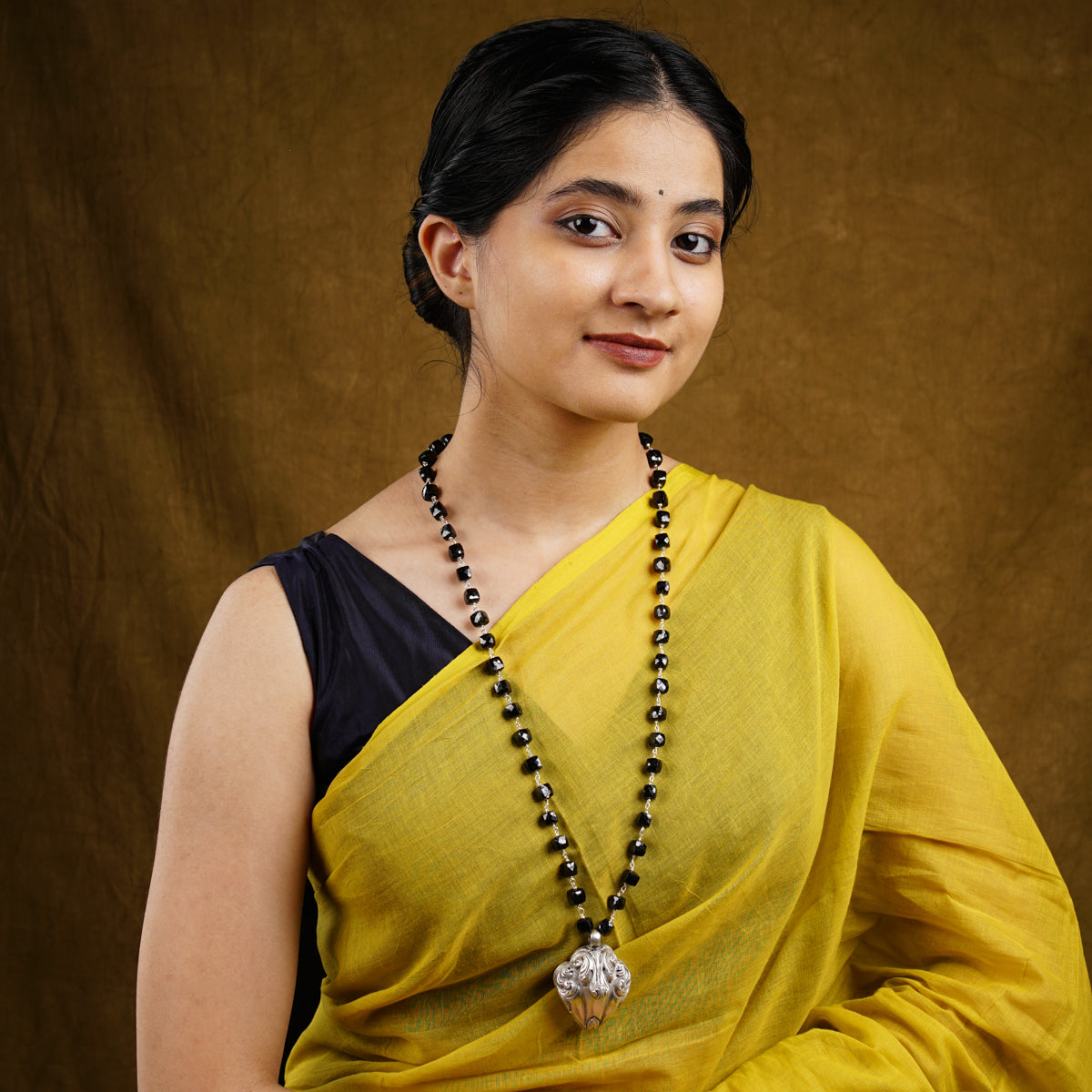 a woman in a yellow sari with a beaded necklace