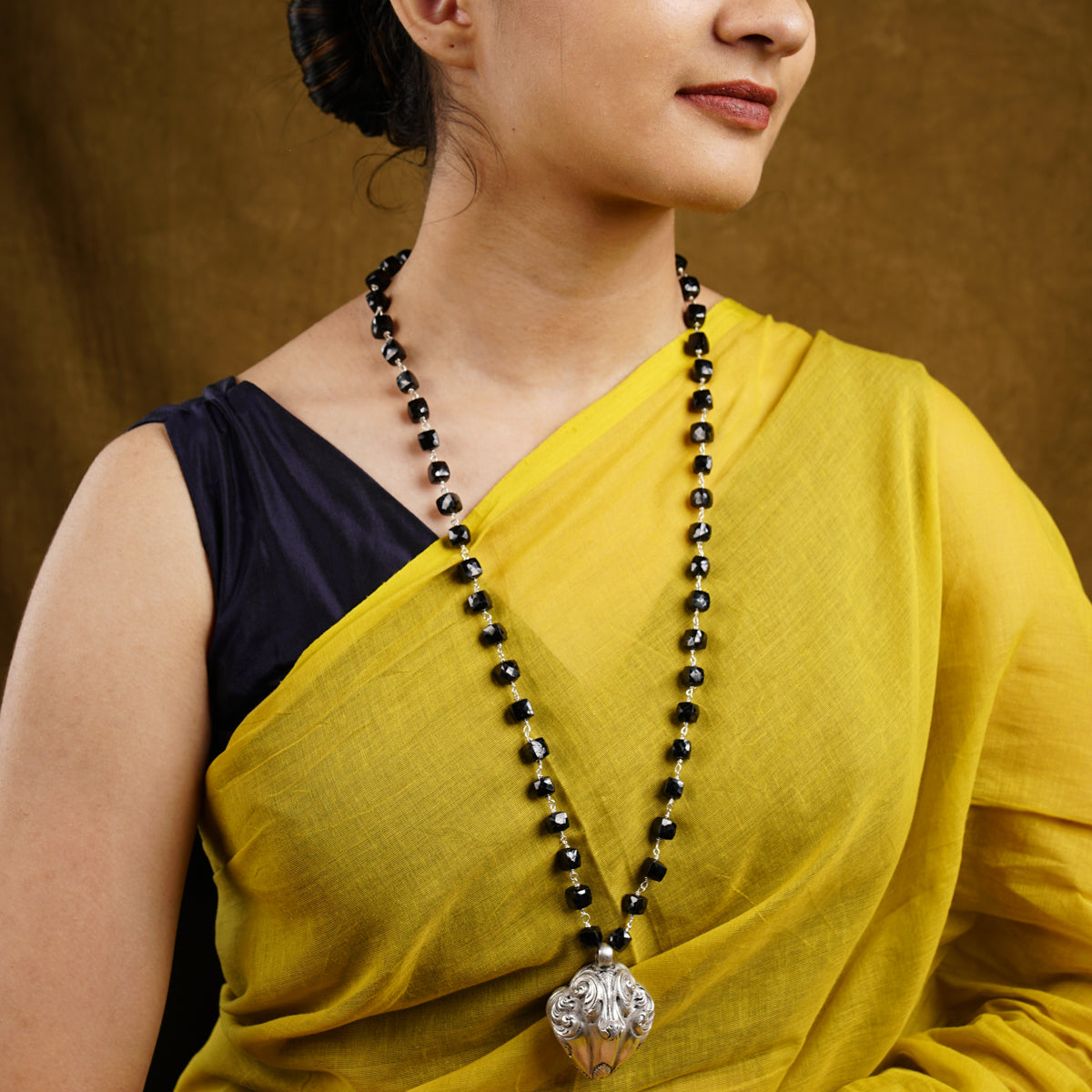 a woman in a yellow sari with a black beaded necklace