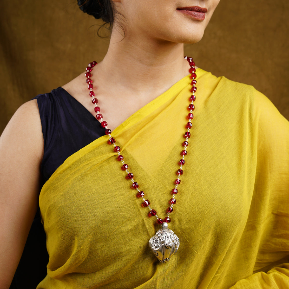 a woman in a yellow sari with a red beaded necklace