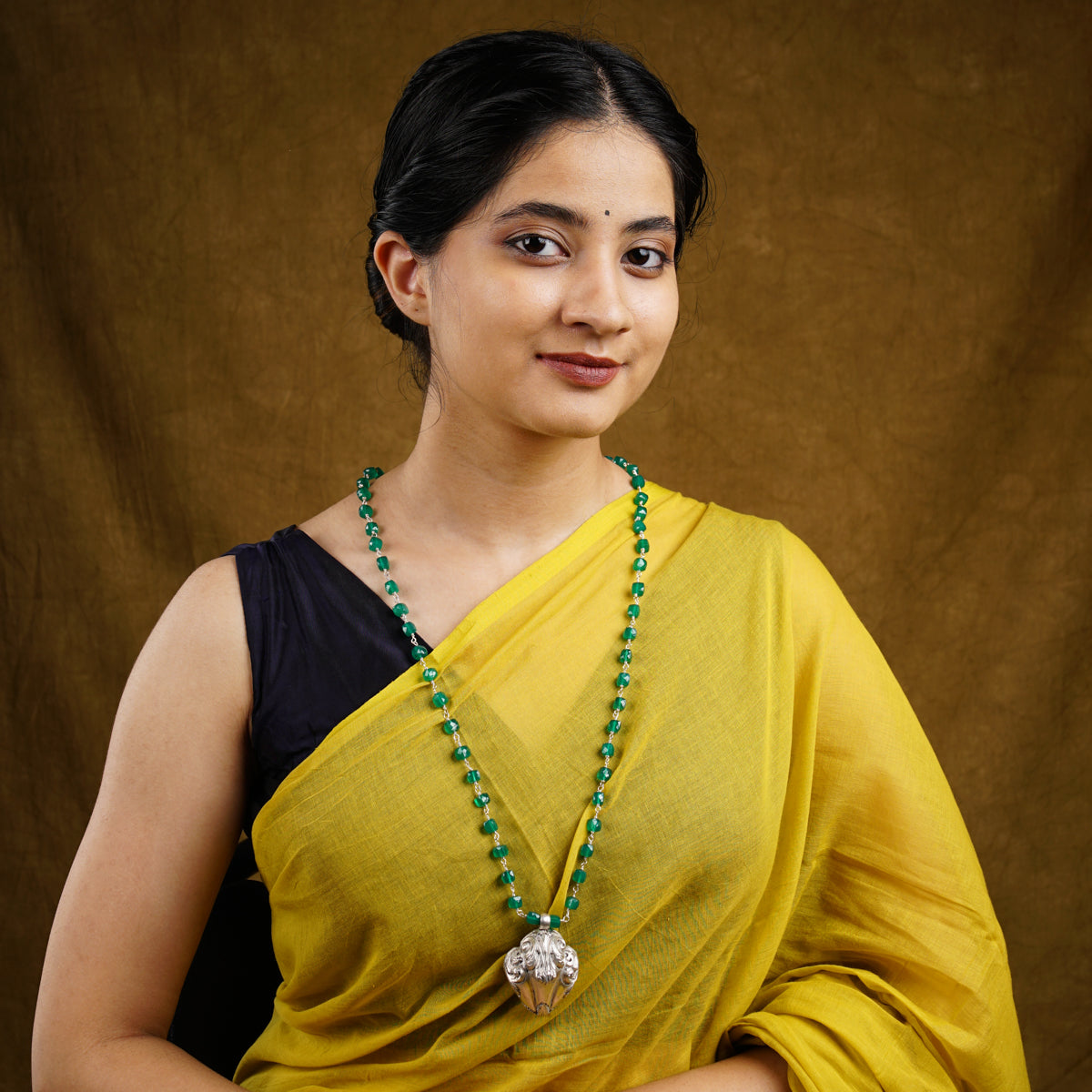 a woman in a yellow sari with a green beaded necklace