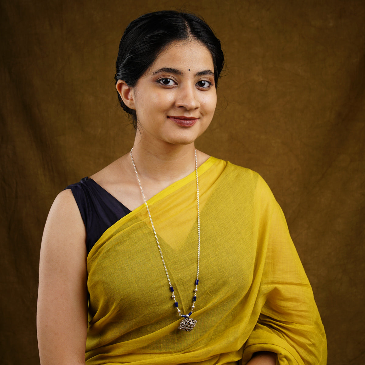 a woman wearing a yellow sari and a necklace