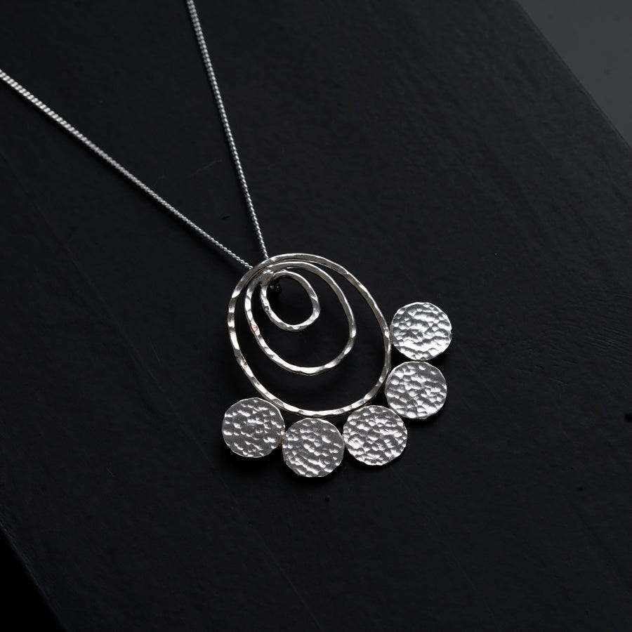 a silver necklace on a black surface