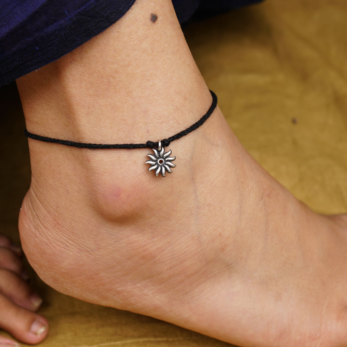 a close up of a person's foot with a flower charm on it