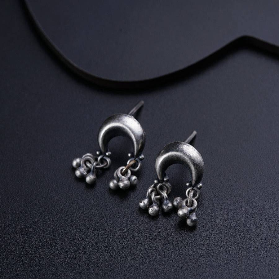 a pair of silver earrings sitting on top of a table
