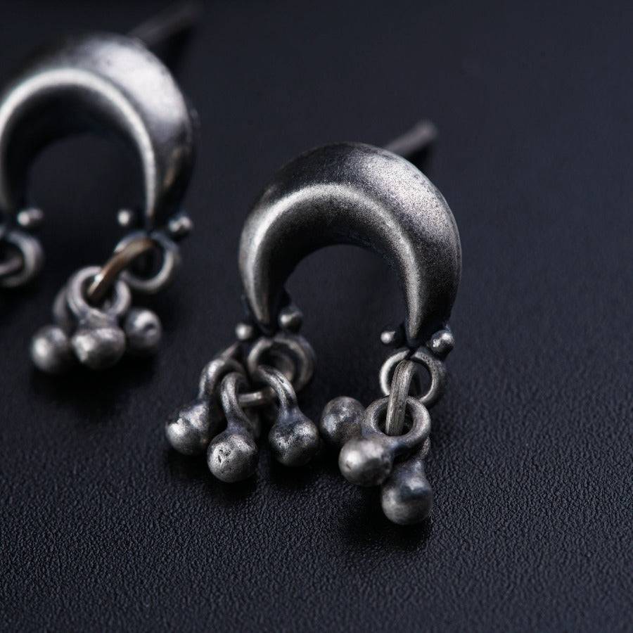 a pair of silver earrings sitting on top of a black surface