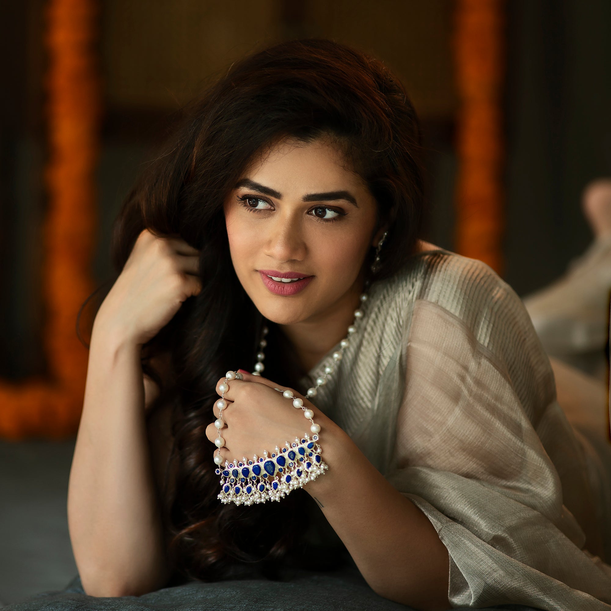 a woman laying on top of a bed wearing a necklace