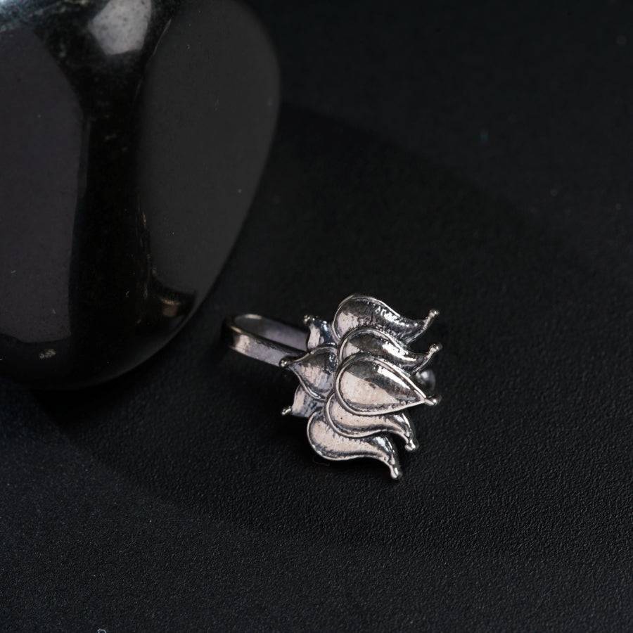 a silver flower ring sitting on top of a black surface